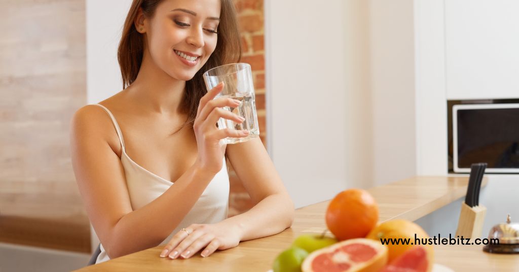 A woman holding a glass and a table with fruits