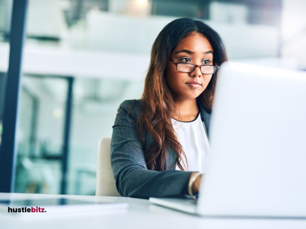 A woman wearing eyeglass doing task in laptop inside the office