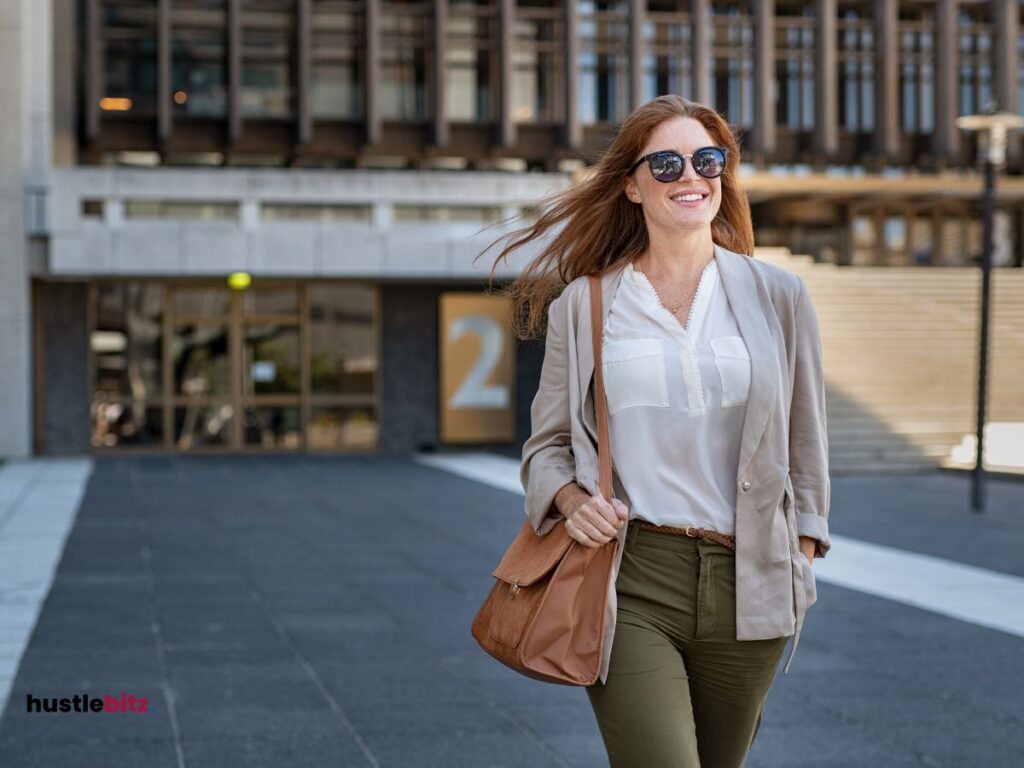 a woman wearing eyeglass while smiles and a background of buildings