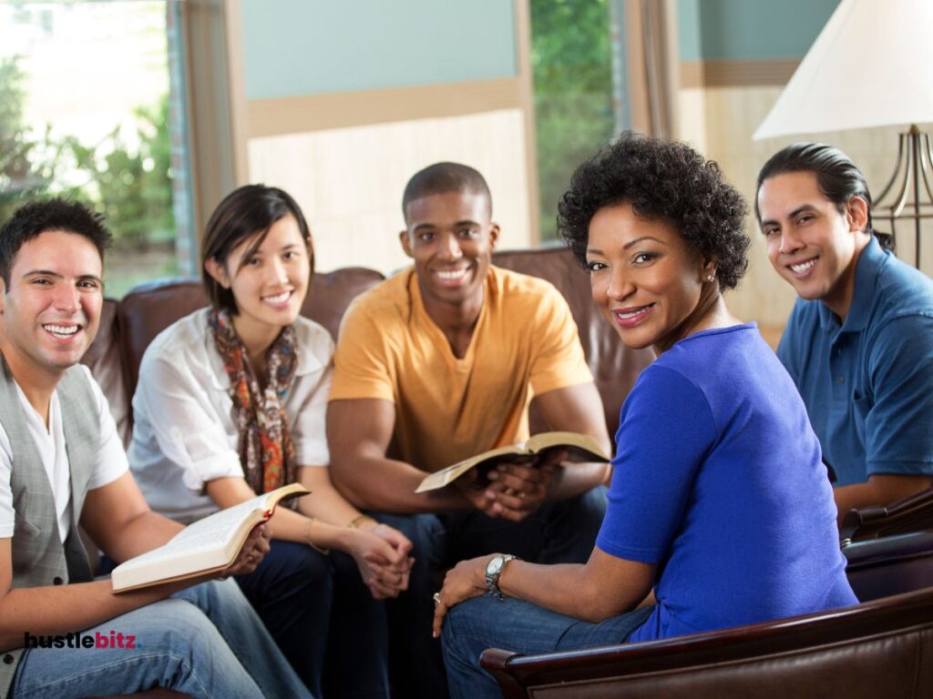 A group of people smiles in front of the camera while two men holding a book