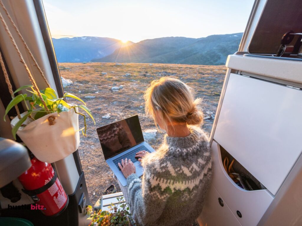 A woman sitting in the van while using laptop in front of the nature