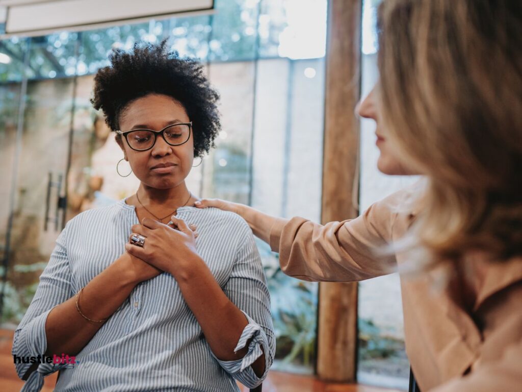 A woman wearing eyeglass and the other woman touch the shoulder of other woman