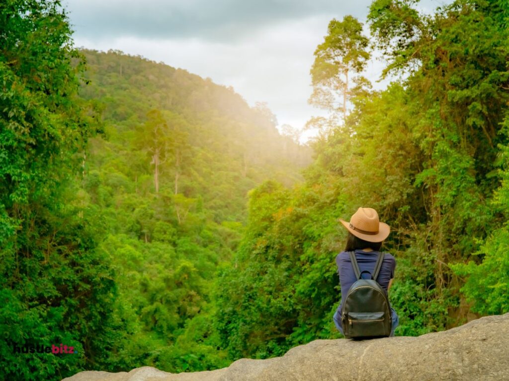 a woman sit down the rock while looking the nature