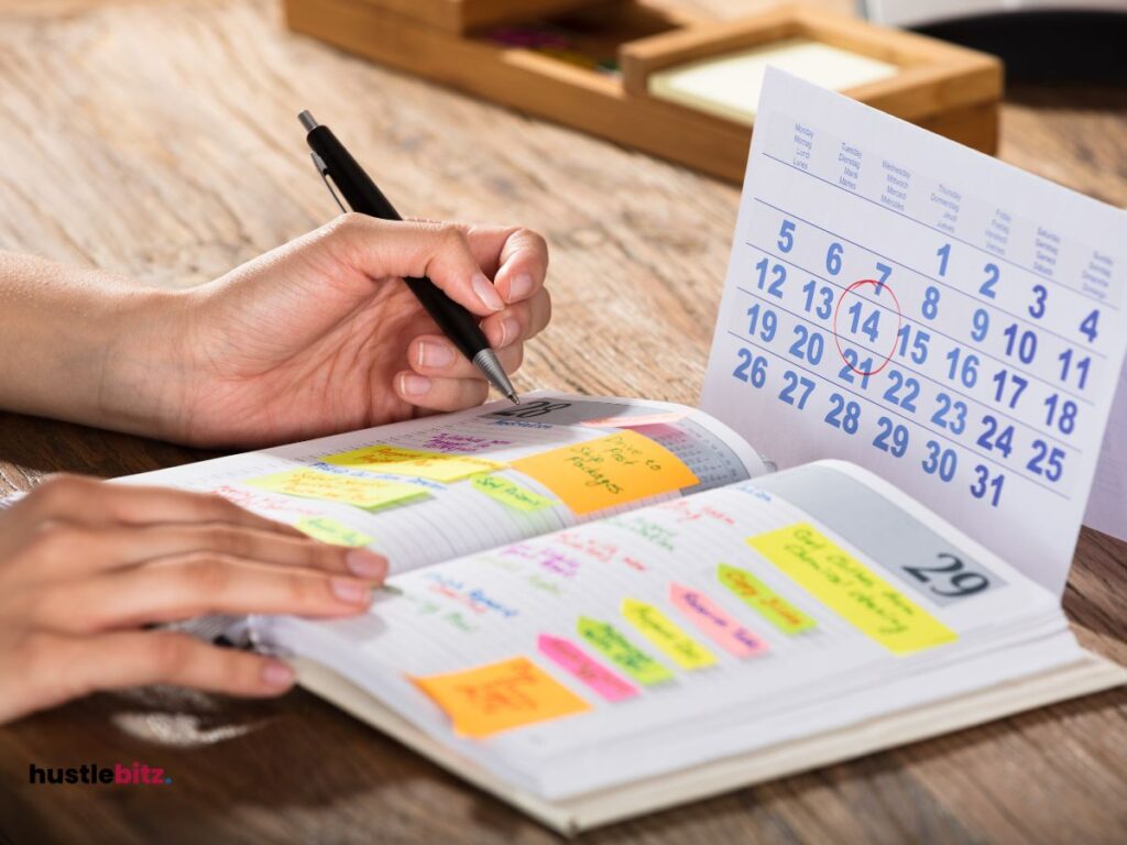 A hand doing writing on the notebook while watching calendar