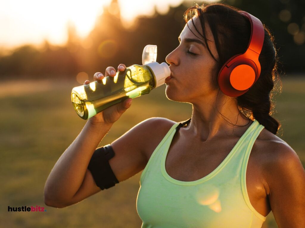 A woman wearing headphone while drinking water