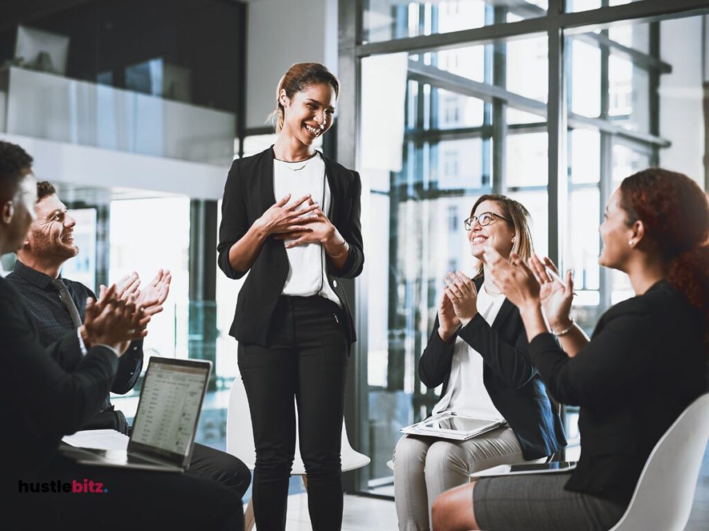 a group of people clapping to the woman standing