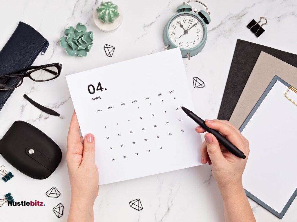 A hands holding a pen and a calendar with clock and other things in the table