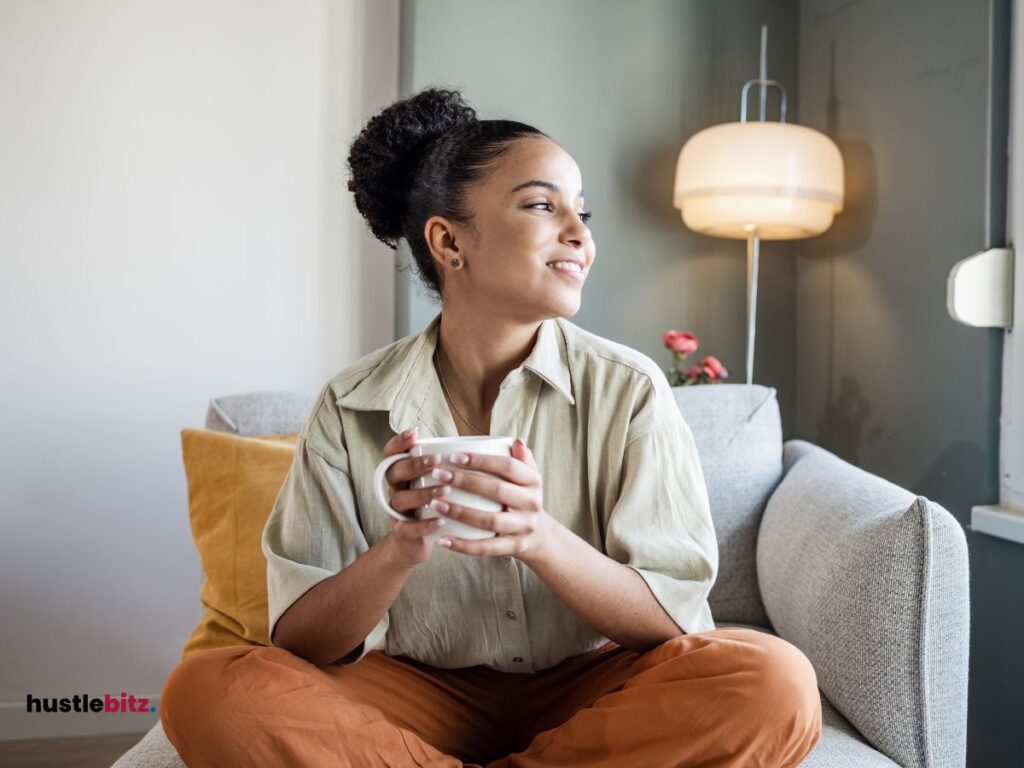 A woman holding a cup smiles while looking at the left side