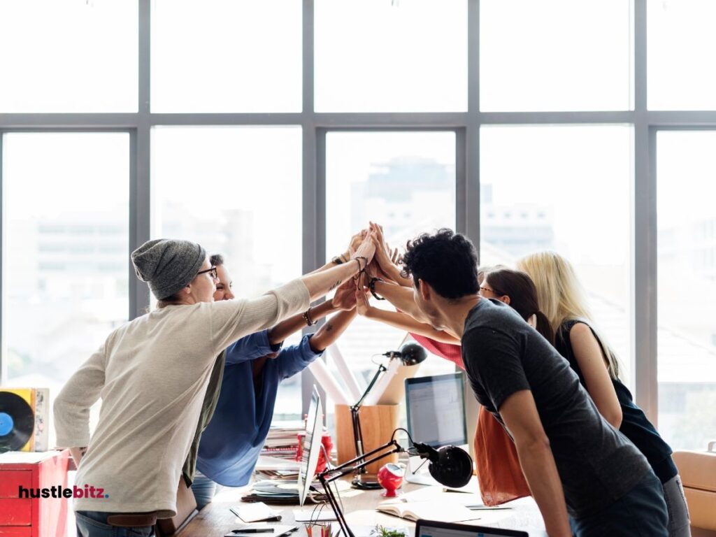 group of people holds their hands together inside the office