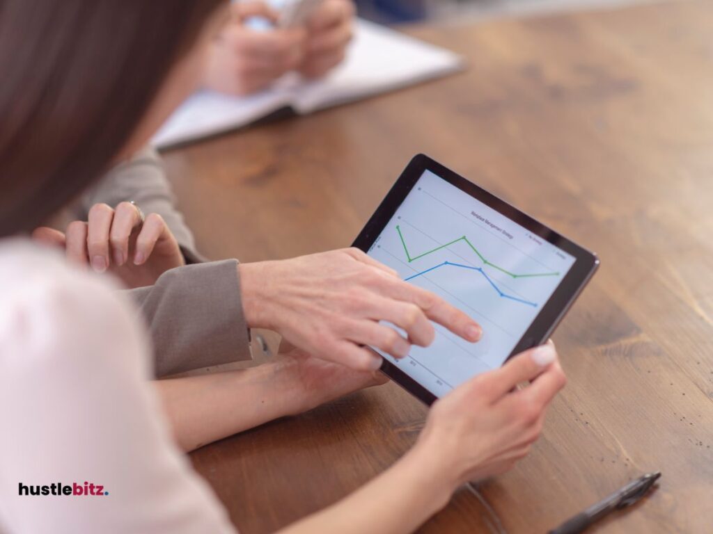 A woman holding a tablet while chatting to other woman