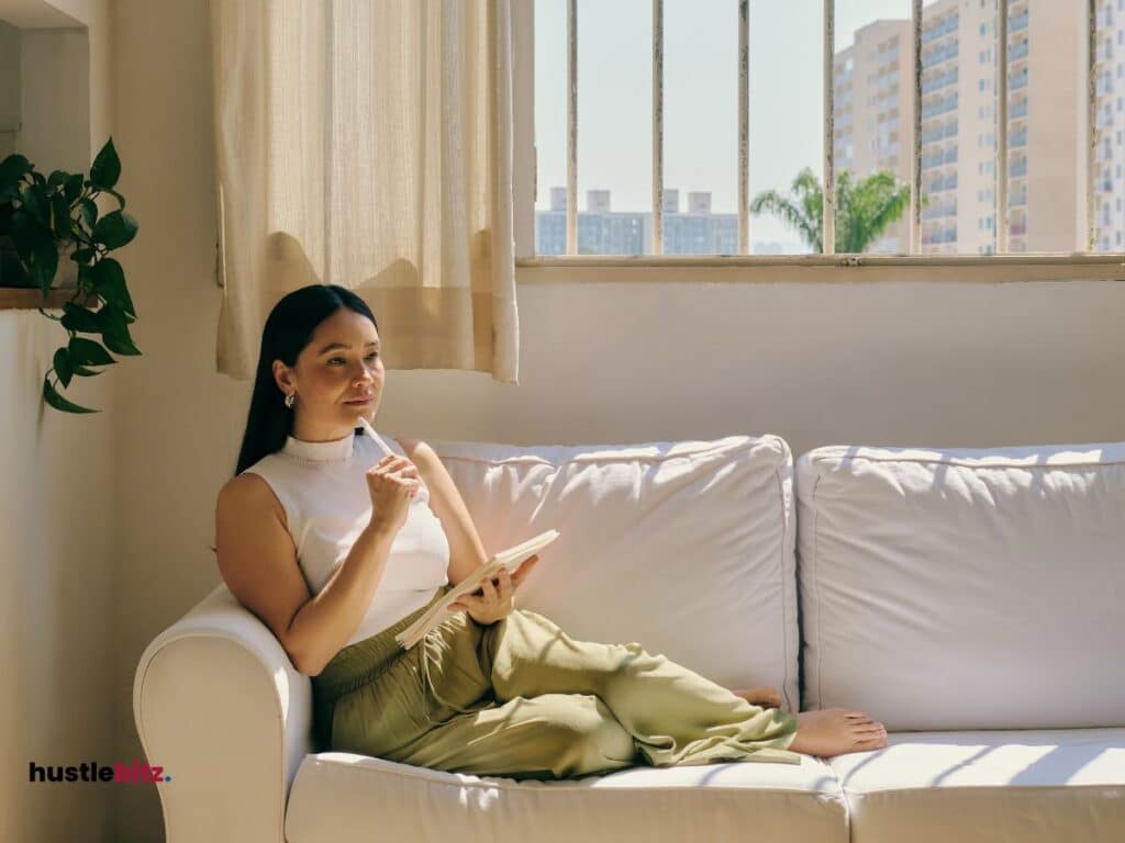 A woman sitting in the sofa holding pen and notebook