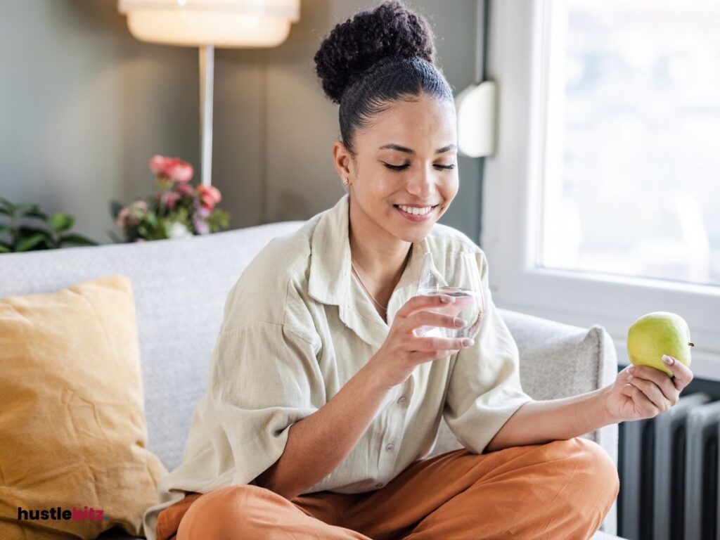 A woman holding an apple and a glass of water