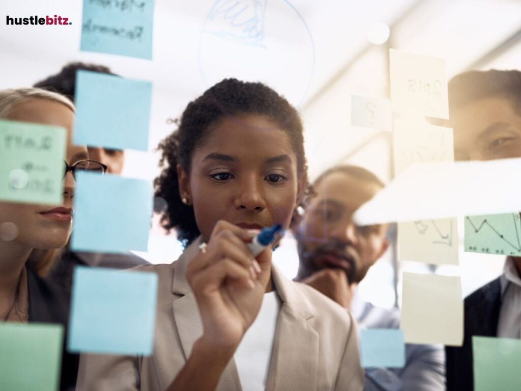 A group of professionals, with a central focus on a woman writing on a transparent board.