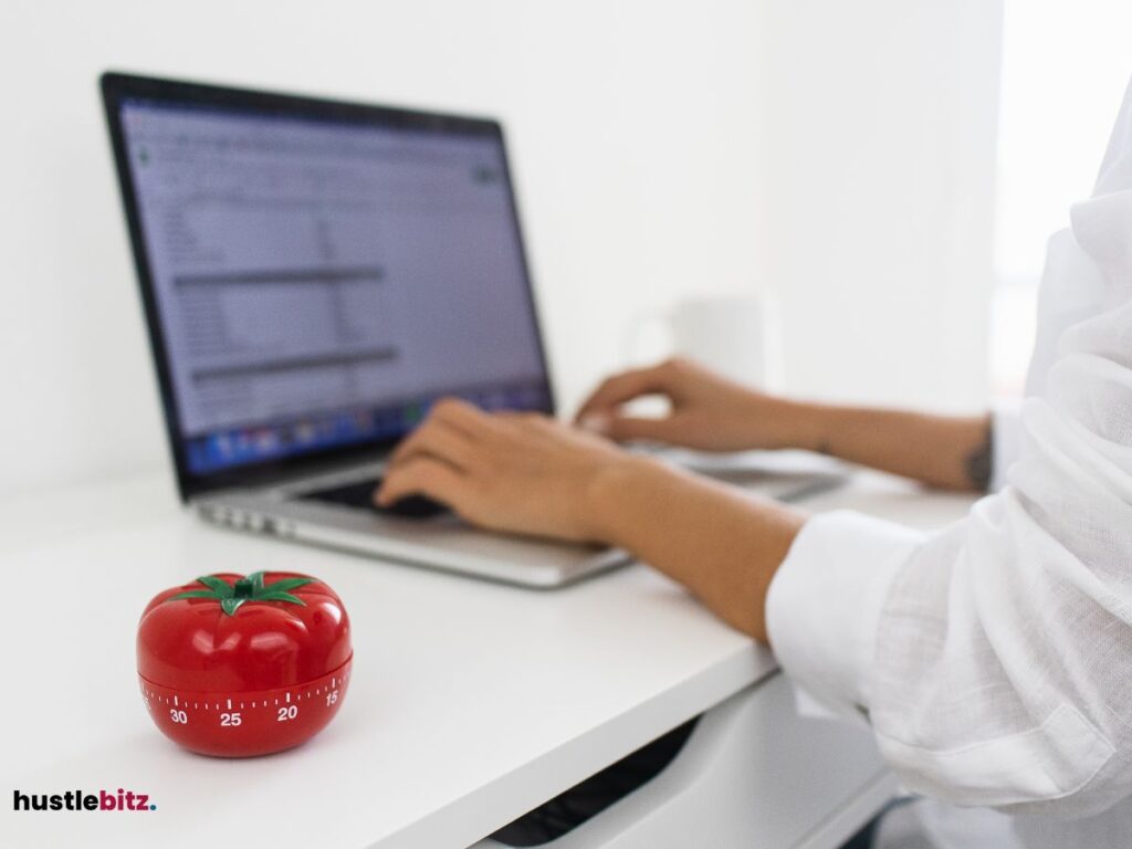 A Pomodoro and a woman looking and typing at the laptop