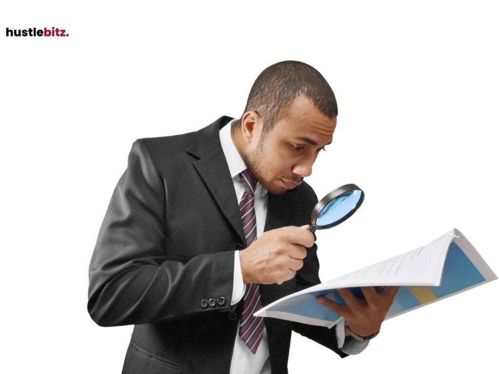 A man in  a suit reading something using a magnifying glass.