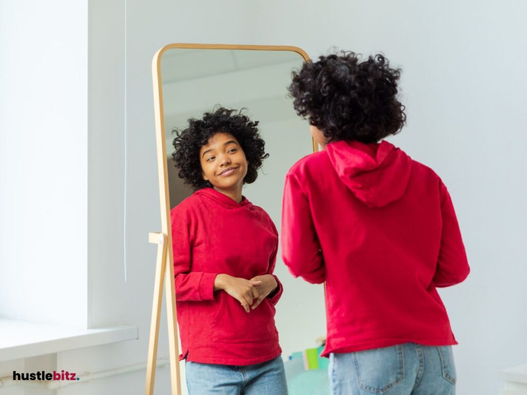 A woman wearing hoddie jacket looking at the mirror