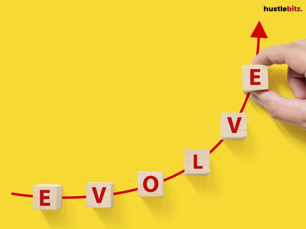 Hand arranging blocks spelling "EVOLVE" with a rising arrow on a yellow background.