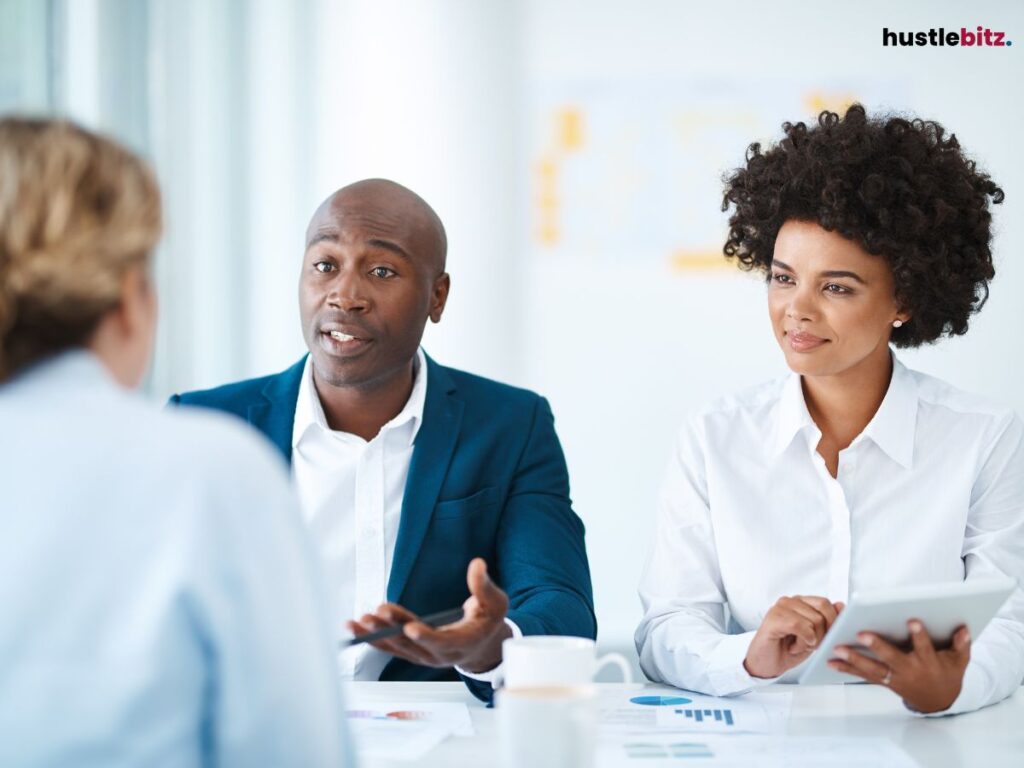 Two people discussing in a business setting, one holding a tablet.