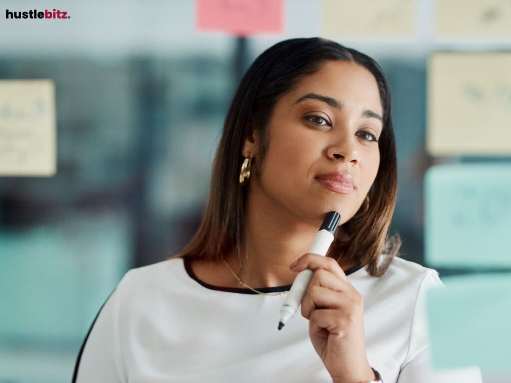 A thoughtful woman holding a marker, surrounded by sticky notes.