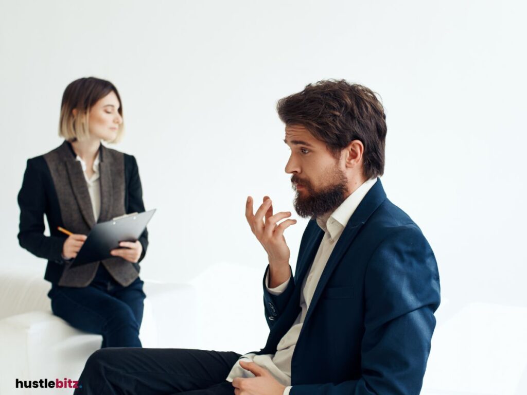 A man in a suit talks to his workmate who is taking notes.