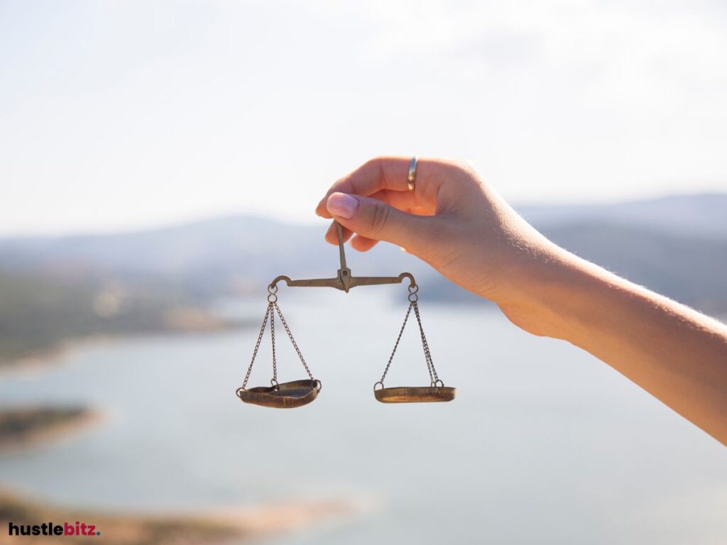 A lady's hand holding a balance scale with nature in the background.