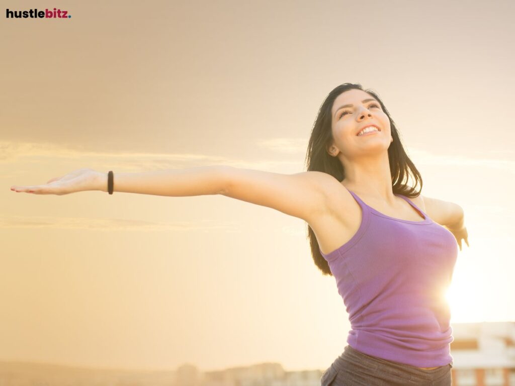 A woman with open arms smiling into the sun.