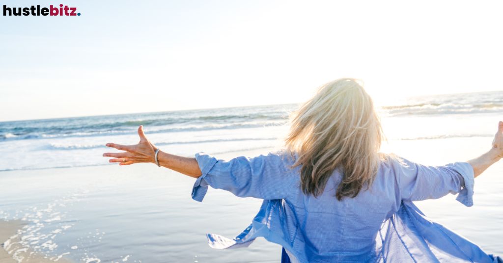 A woman at the beach streatching her arms wide.