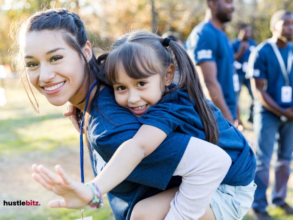 A woman giving a young girl a piggyback ride during a community event.