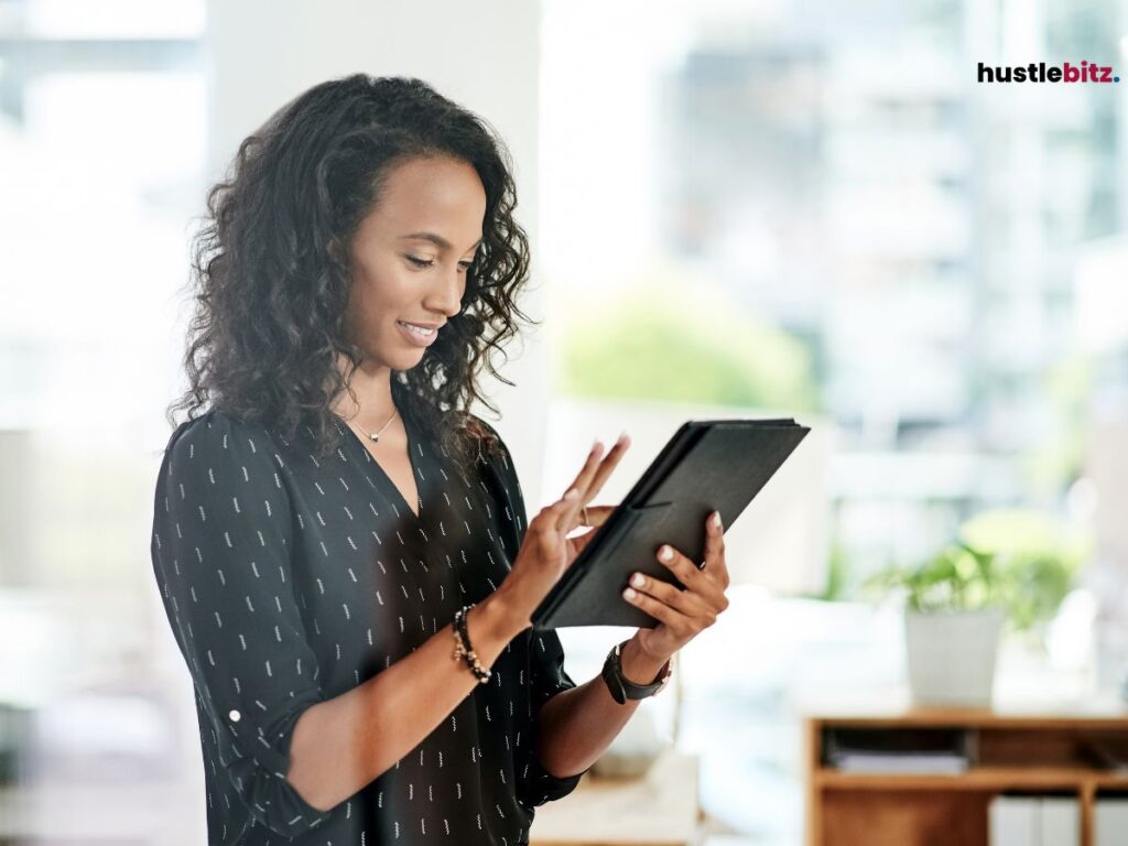 A woman smiling while working on a tablet.