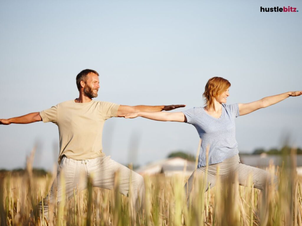 Man and woman doing yoga in a field.