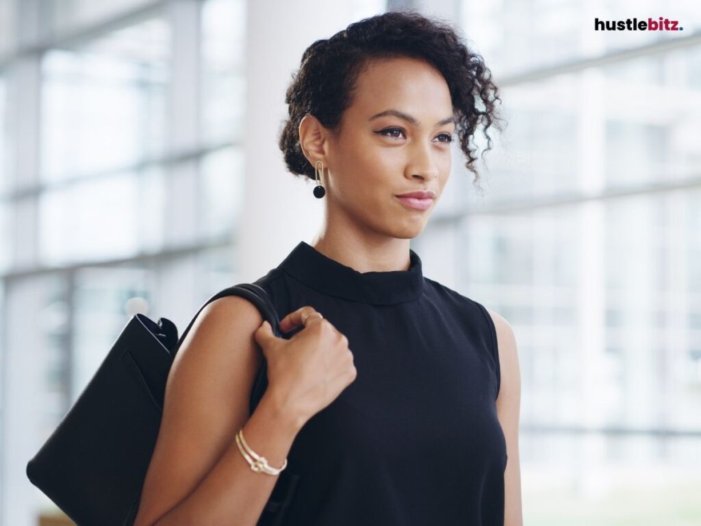 A confident woman carrying a bag, walking in a modern office.