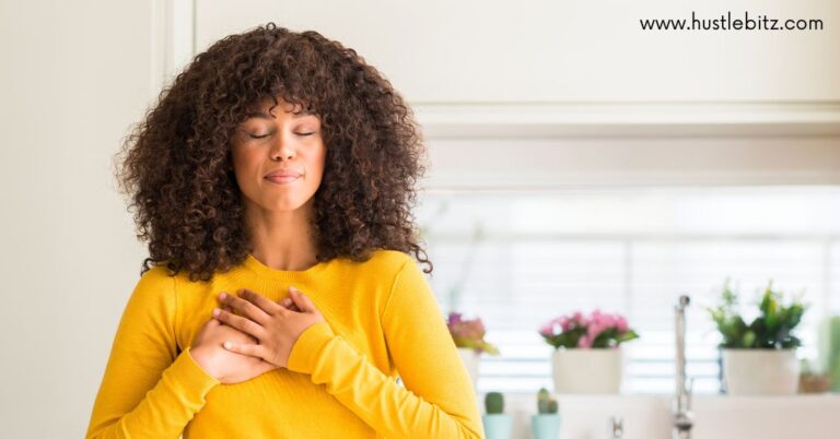 A woman in a yellow shirt, eyes closed, hands on her chest, and in deep relief.