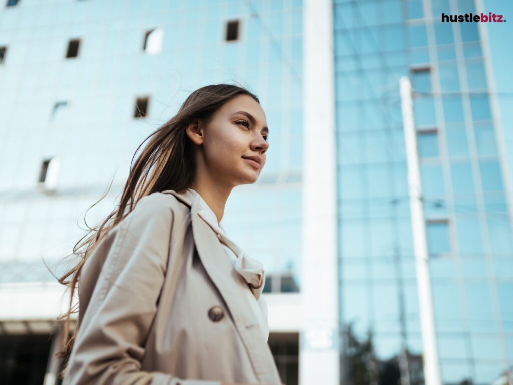 A confident woman in a beige coat looking forward.