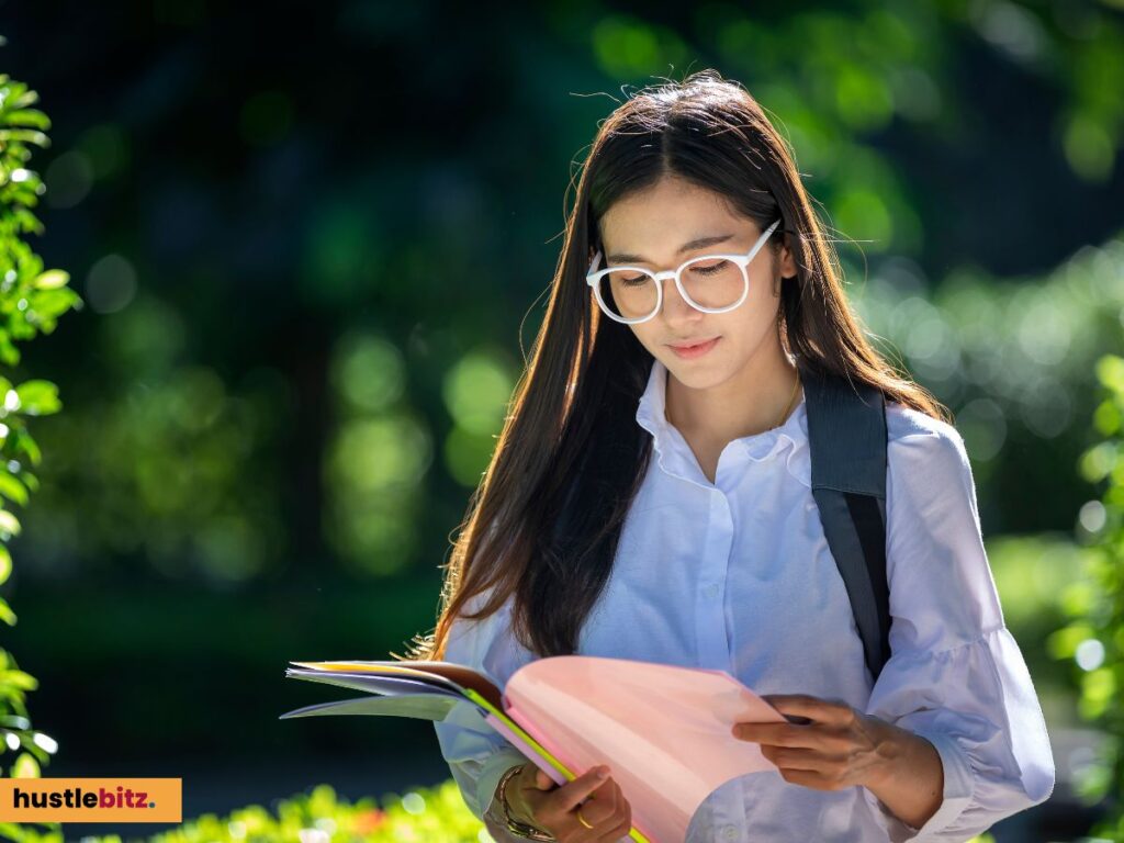 A woman with glasses reading something while walking.