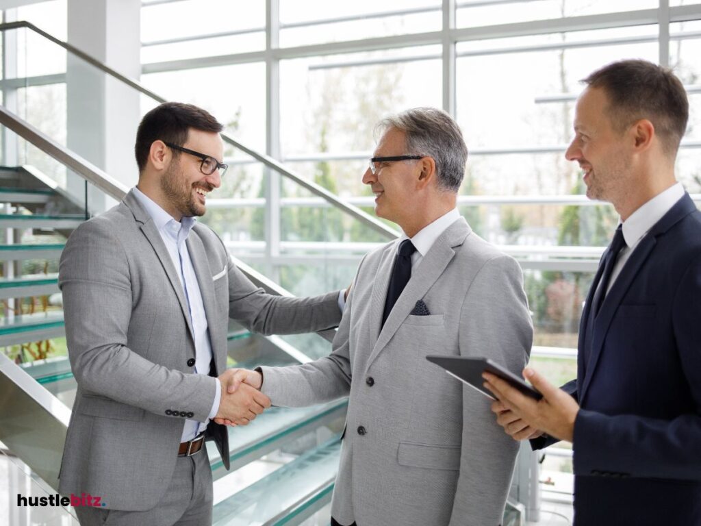 three men smiles and two men shake hands
