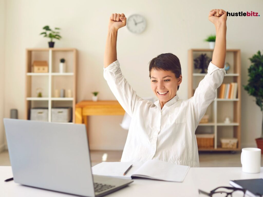 A woman raise her two hands representing victory and inside the office
