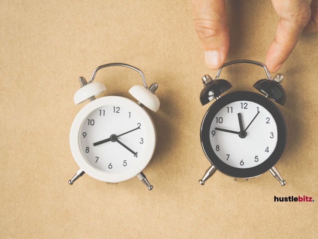 A hand holding the black clock beside the white clock