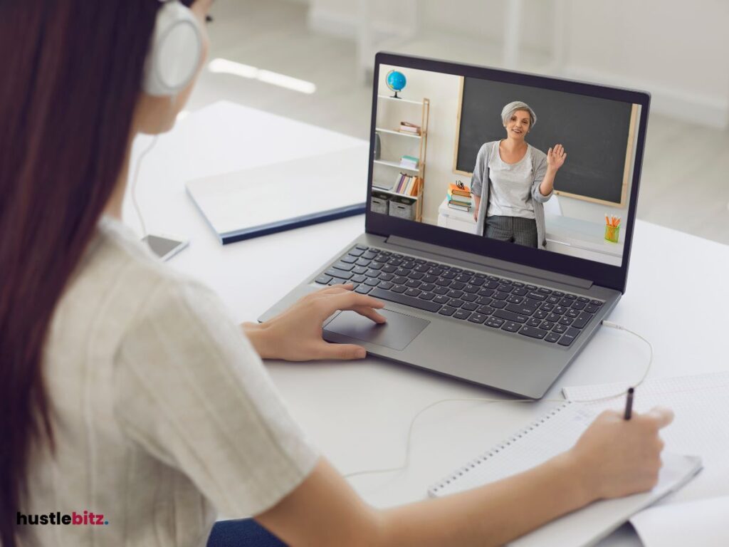 A woman looking at the laptop and doing writing