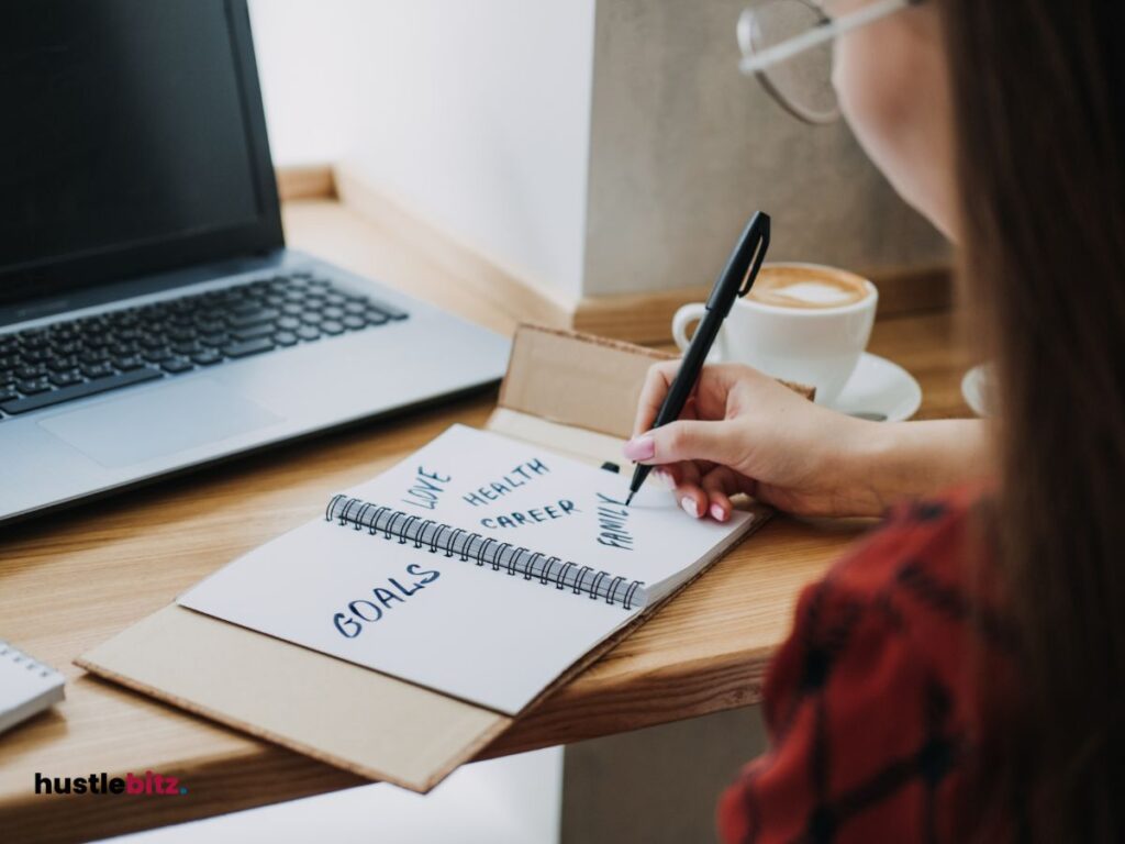 a woman doing writing and a laptop in the table