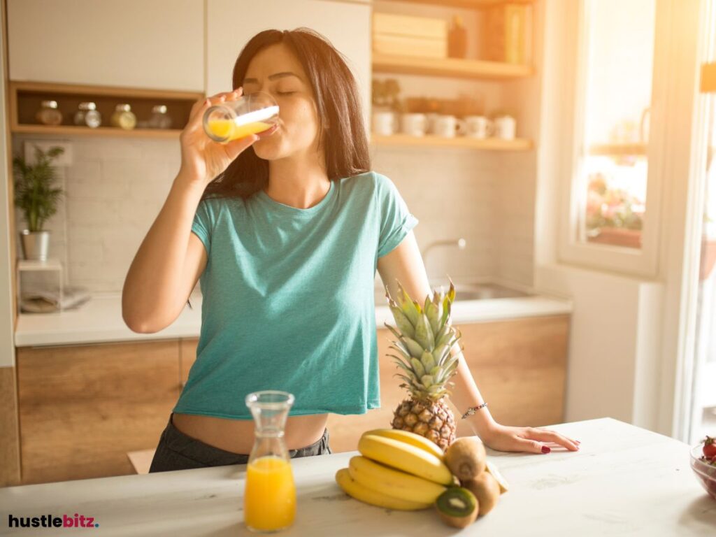 A woman drinking a glass of fruit juice.