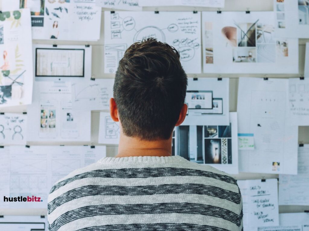 Man looking at a wall filled with notes and sketches.