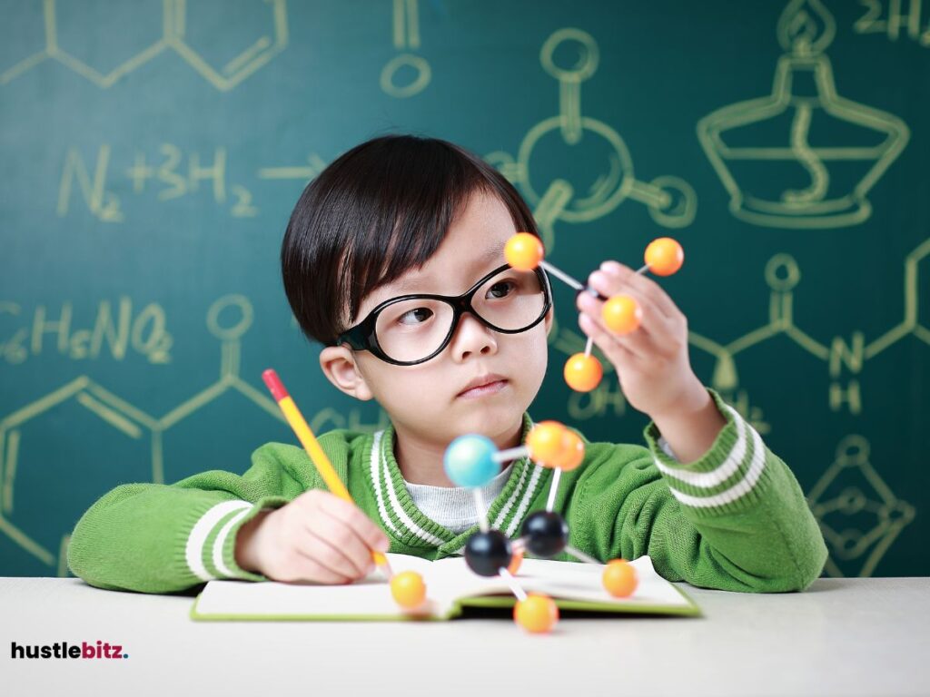 A young child wearing glasses is studying a molecular model with a pencil in hand.