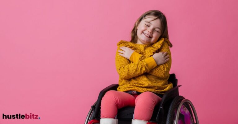 Smiling child in a wheelchair hugging themselves against a pink background.