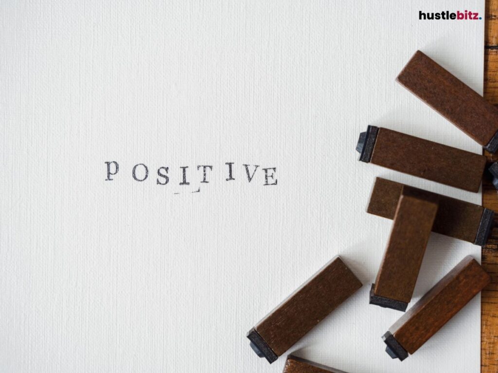 Stamped letters spelling "Positive" on a plain surface, next to scattered stamps.