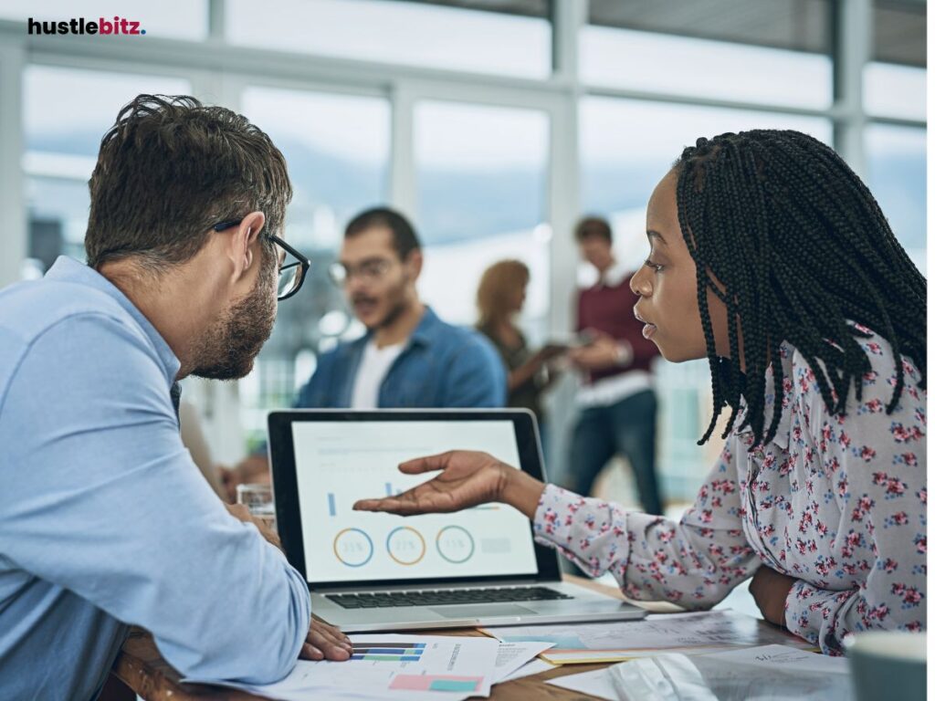 A woman explaining data insights to a colleague in an office setting.