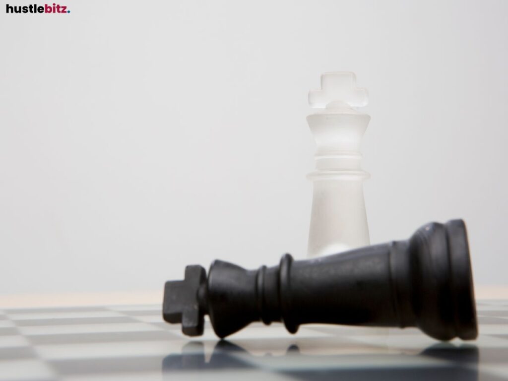 A two king chess piece, the white one standing and the black falls.