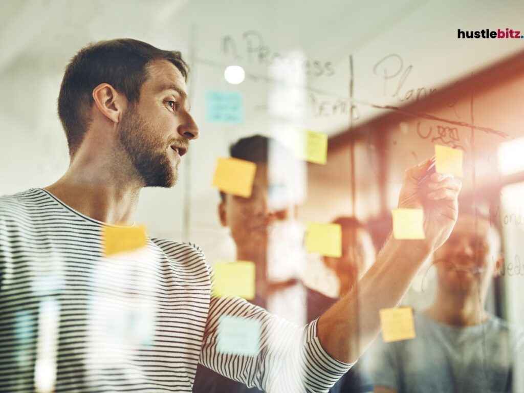 A man writing on a glass board covered with sticky notes, engaging in planning and brainstorming. 