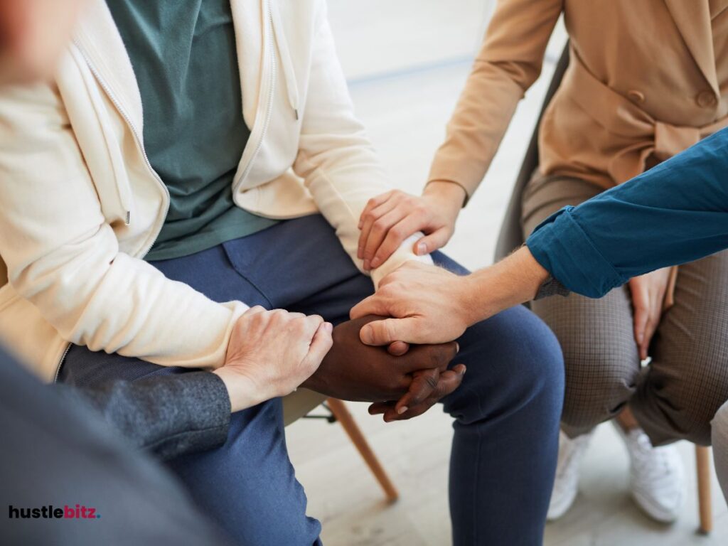 A close-up of people holding hands in a supportive group setting.