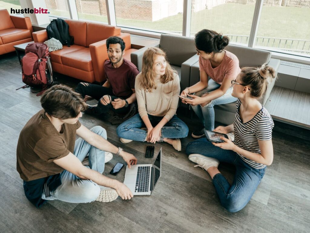 Group of five people having a casual discussion on the floor.