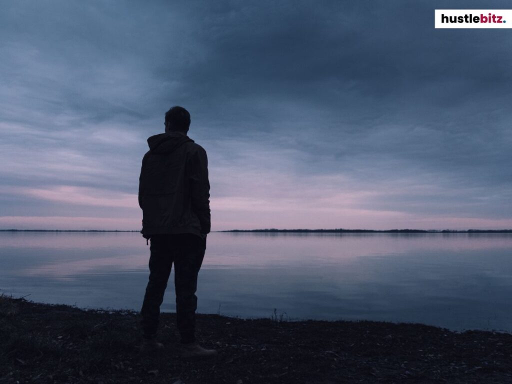 A man standing near the sea at dawn.